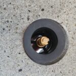 Detalle de una válvula de desagüe en un lavabo de piedra moteada