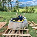River stone bathtub, with a person seated inside, displayed outdoors